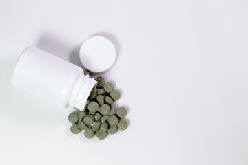 Frasco de Medicamentos en fondo blanco, medicina natural, pastillas color verde.
