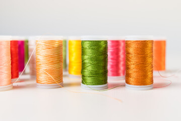 green and orange, close-ups of colored threads, dressmaker, atelier, seamstress, sewing clothes, embroidering fabric, needle and thread, selective focus