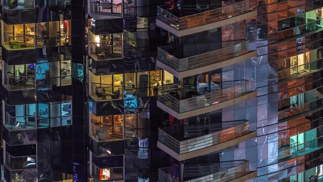 Night view of many glowing windows in apartment residential tower timelapse. High rise illuminated skyscraper with lights in rooms