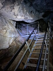 Escalier dans une grotte souterraine. Intérieur d'une mine. Paroi rocheuse d'une caverne. - obrazy, fototapety, plakaty