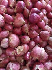 Red onions on market stall. Closeup of fresh raw onion food background. Organic onions top view. Food background. Selective focus. Red onions in plenty.