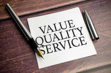 value quality service words on paper sheet and pen on wooden background