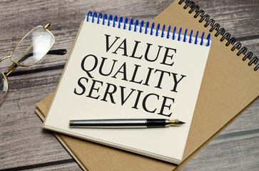 value quality service symbol on notepad and glasses and pen