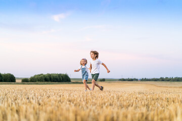 Naklejka na ściany i meble Happy and free people, children run through the beveled field of wheat