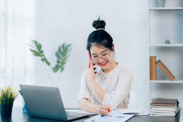 Young asian businesswoman beautiful charming smiling and talking on the mobile phone in the office