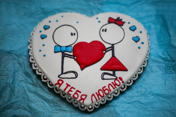 delicious white gingerbread with a pattern. a pair of boy and girl with a red heart in their hands. the inscription I love you in Russian.
