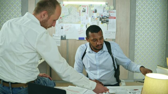 Diverse detectives discussing clues on homicide investigation at police department.Caucasian sergeant arguing with african american detective. FBI agent highs a five and smiles.High quality 4k footage