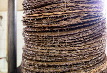 Closeup of stack of fiber mats with grinded olive paste during pressing of olive oil on artisanal...