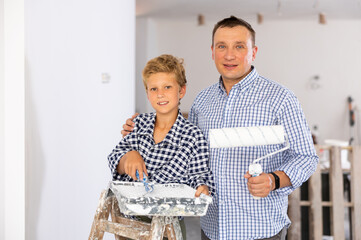 Portrait of cheerful father and son with a paint roller. The concept of helping parents to repair the apartment