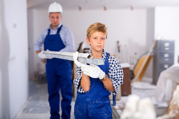Portrait of smiling boy carrying building materials, working together with father, renovating house