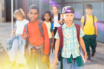 Group of schoolchildren with backpacks going together to open air lesson