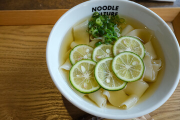 Close up tanuki udon, japanese noodles with fresh lime slice and cold soup, summer dish.