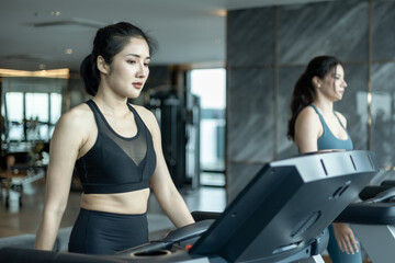 Fototapeta na wymiar woman working out in gym, Two young Asian women jogging on a treadmill in gym, Female athlete running on a treadmill