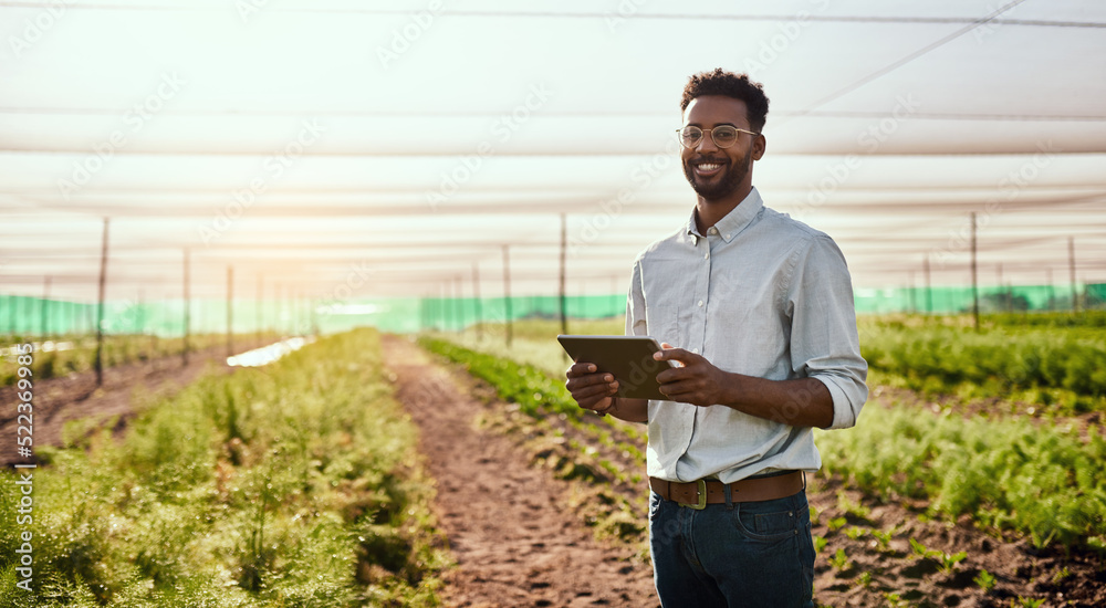 Poster modern farmer working on a tablet on a farm and checking plants growth progress with an online app o
