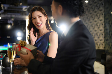 A hand to present at a bar at night A beautiful woman and a bearded man Present