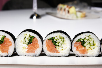 Sushi on a white background in sesame seeds with avocado and nigiri. Futomaki with salmon and cucumber. Food.