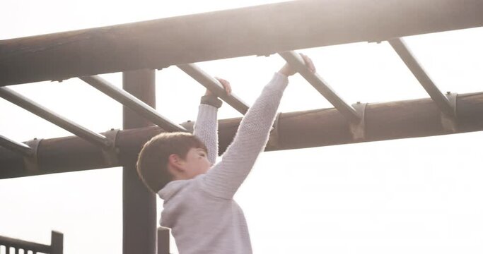Fun, carefree and active little boy playing on monkey bars outdoors at a playground. Child having fun climbing, looking happy, content and confident, Kid being playful and enjoying free playtime