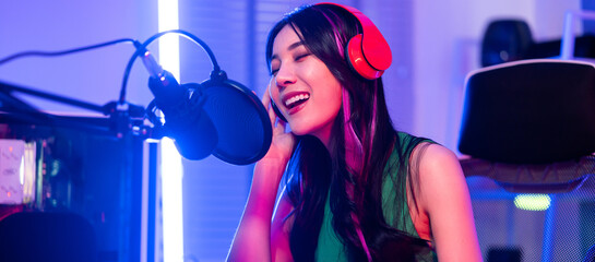 Asian attractive audio DJ woman speaks into microphone to broadcasting © Kawee
