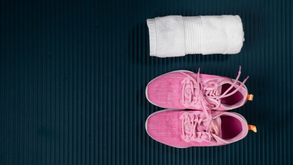 Sneakers and rolled up towel on a workout mat with space for text