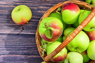 large ripe red green apple close up with drop of water in wicker basket on dark wooden boards. Top view, flat lay