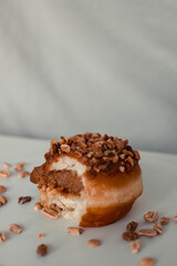 Vertical closeup shot of a bitten walnut donut with filling on a white plate with nuts