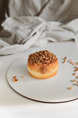 Vertical shot of a walnut donut with filling on a white plate with nuts