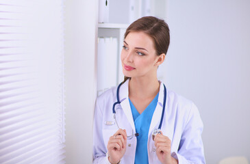 Woman doctor is standing near window with crossed arms,isolated