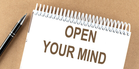 OPEN YOUR MIND text on a notepad with pen, business concept