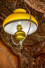 Fototapeta na wymiar Yellow ancient lamp decoration with wood carving background on the terrace of the house