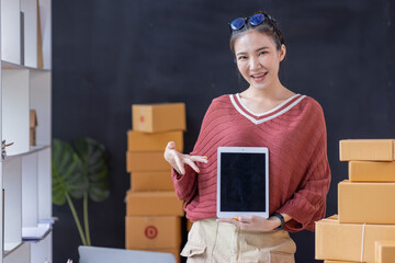 SME Online seller Young Asian woman freelance working on laptop tablet and box, checking online...