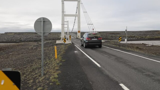 Bridge in rural Iceland with car driving over with gimbal video walking forward in slow motion.