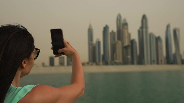 Girl taking picture of Dubai skyline from boat