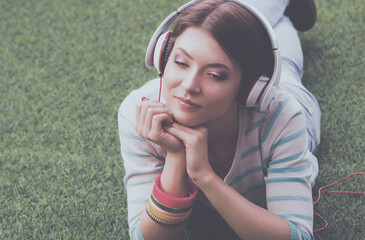 Woman listening to the music lying on green grass