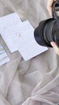 Photographer girl taking pictures of wedding invitations with rings