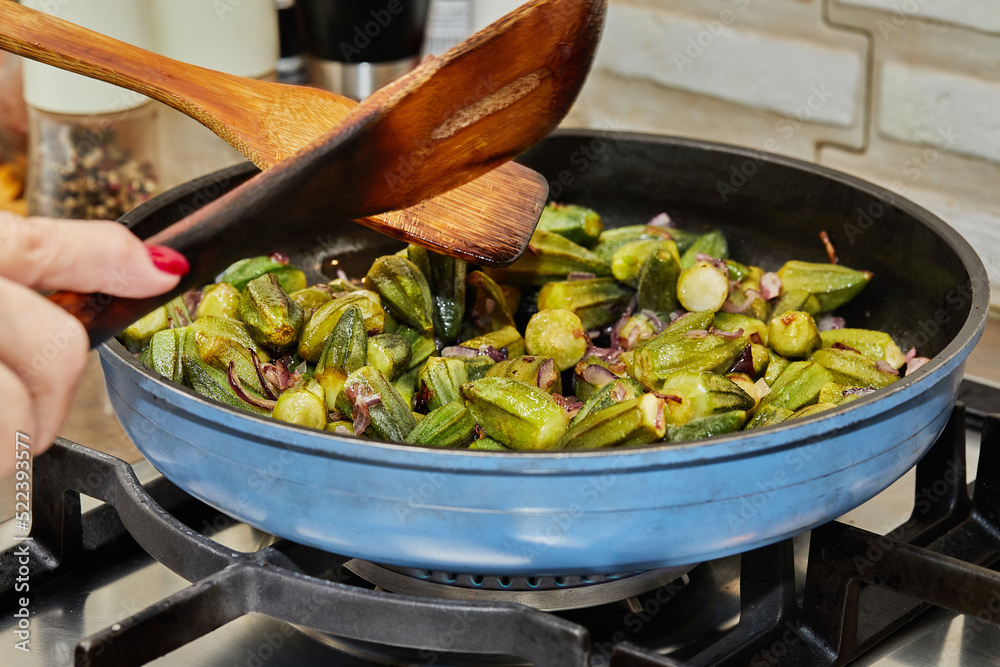 Canvas Prints The chef stirs the okra into the pan with the fried purple onions