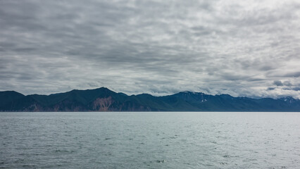 The picturesque coastline of Kamchatka. Hills and steep cliffs against a cloudy sky and ocean. Avacha Bay.