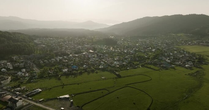 Panoramic View Of Misty Townscape With Silhouette Mountains At Background In Bakuriani Ski Resort In Georgia. Aerial Wide Shot