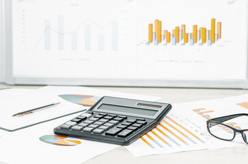 Obraz premium Finance and business concept. calculator on financial graphs on office desk, laptop and glasses. Accounting budgeting or market analysis. Web banner with copy space