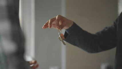 Handover of keys to new flat. Real estate agent giving key with house shaped keyring to man. Moving into new apartment concept. - Powered by Adobe