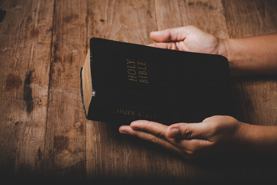 Close up of christian woman hand on holy bible are pray and worship for thank god in church with black background, concept for faith, spirituality and religion
