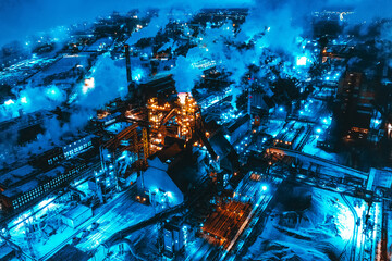 Night top view of steel plant at night with smokestacks and fire blazing out of the pipe. Industrial panoramic landmark with blast furnance of metallurgical production. 