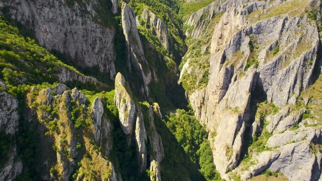 Aerial drone view of a rocky canyon in Romania. Rocky cliffs with sparce vegetation. Fields in the distance