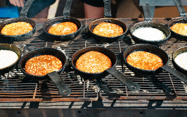 Cooking hash browns in pan on grill. Close-up of fried potato pancakes outdoors. Popular dish of European cuisine