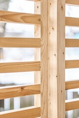 Stylish decorative partition wall made of thin wooden planks stands on contemporary country house terrace on winter day closeup