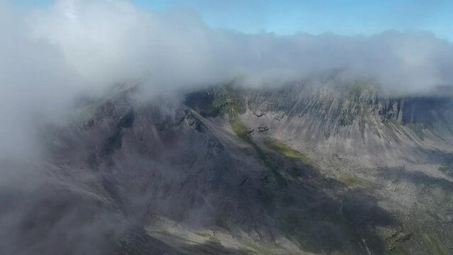 A drone shot of people on a peak in the Scottish highlands. Beautiful scenery and clouds scattering the area.