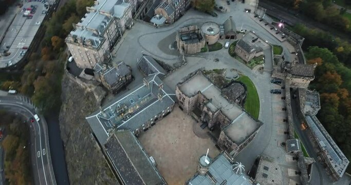 A stunning drone view looking down on Edinburgh castle at sunset, slowly panning up to see Princes street and the new town in the distance.