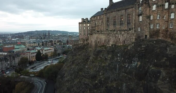 Drone shot panning around Edinburgh Castle on a dark, cloudy morning. The shot finishes looking over the top of the castle over to Princes Street