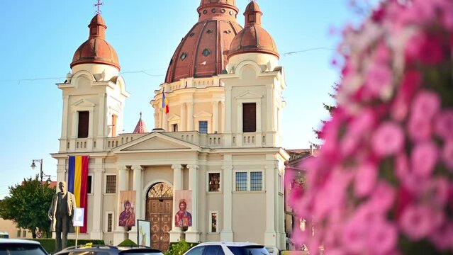 Church of the Annunciation and Statue of Emil Dandea in the centre of Targu Mures, Romania. Flowers and greenery
