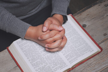 Naklejka premium Human hands praying to god with bible on wooden table. Man praying for God's blessing for a better life. Christian Crisis Prayer to God.