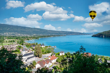 yellow hot air balloon flying over Annecy lake in the morning, France